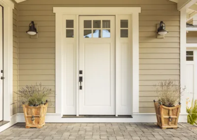 A white front door with two potted plants.